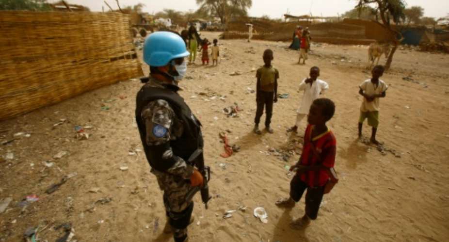 Sudanese children stand next to a member of the UN-Afrcian Union mission in Darfur UNAMID, a mission that expects significant troop cuts under a proposal for strategic review.  By ASHRAF SHAZLY AFPFile