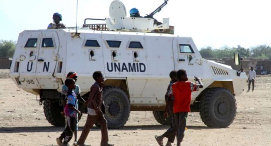 Sudanese children walk past an armoured vehicle of the United Nations and African Union peacekeeping mission UNAMID in Kalma Camp for internally displaced people in Nyala, the capital of South Darfur, on Wednesday.  By - AFP