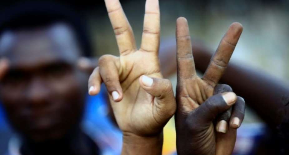 Sudanese demonstrators flash V-for-victory signs as they gather outside the military headquarters in Khartoum in the capital Khartoum on May 20, 2019.  By ASHRAF SHAZLY AFP