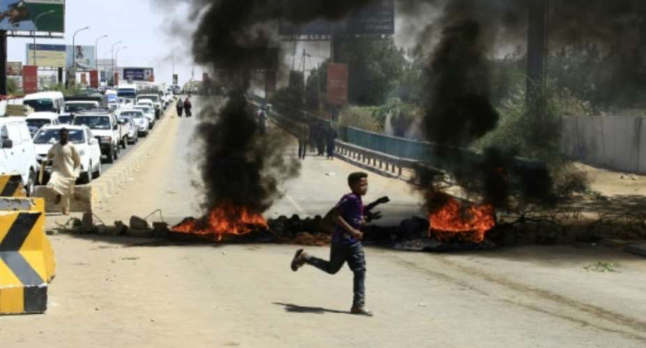 Sudanese demonstrators set fire to tyres to block a Khartoum road as the five-month protests show no signs of abating.  By EBRAHIM HAMID AFP