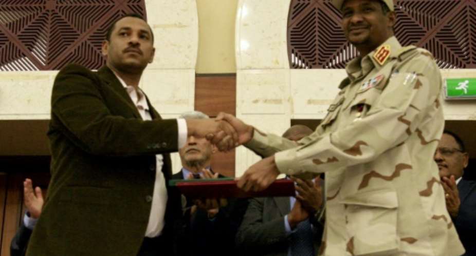 Sudanese deputy chief of the ruling miliary council Mohamed Hamdan Dagalo and protest movement Alliance for Freedom and Changes leader Ahmad al-Rabiah shake hands after inking a power-sharing agreement.  By Ebrahim HAMID AFP