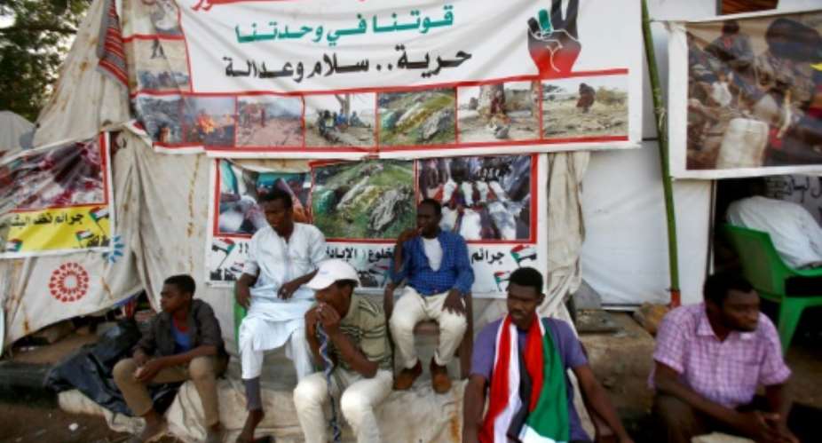 Sudanese men displaced from Darfur sit next to a tent outside the military headquarters in the capital Khartoum at the ongoing sit-in.  By ASHRAF SHAZLY AFP