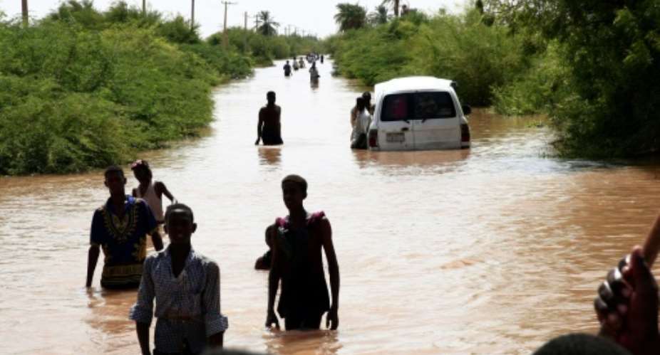 Sudanese people walk a flooded road in Wad Ramli village on the eastern banks of the Nile river.  By Ebrahim HAMID AFP