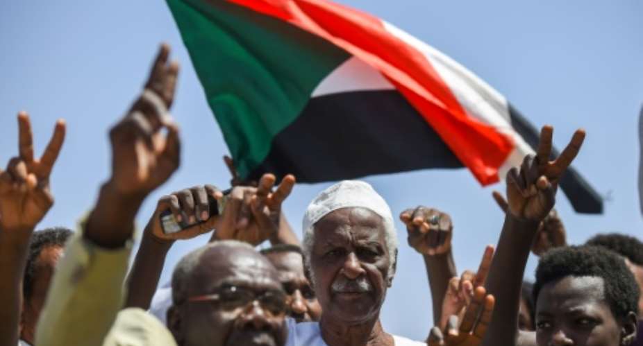 Sudanese protesters chant slogans, flash V-for-victory signs and wave the national flag at the sit-in outside the army headquarters in the capital Khartoum on May 14, 2019.  By Mohamed el-Shahed AFP