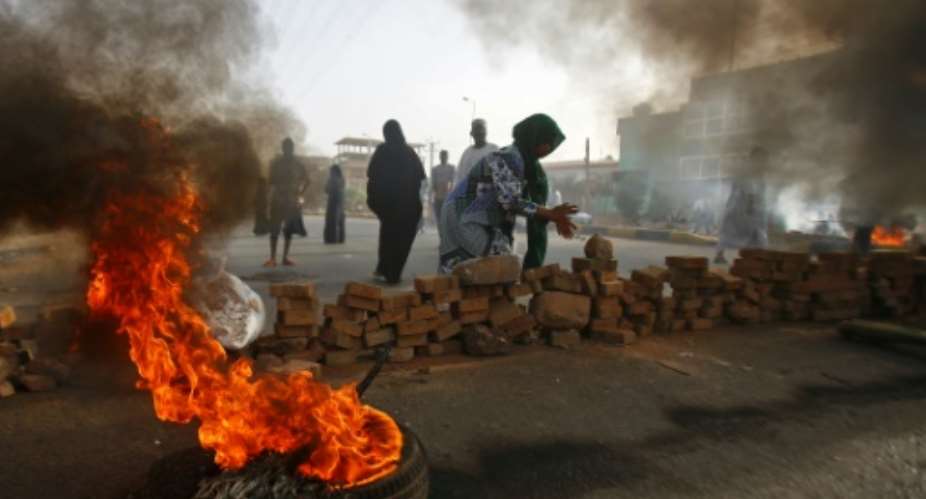 Sudanese protesters close Street 60 with burning tyres and pavers as military forces tried to disperse a sit-in outside Khartoum's army headquarters on June 3, 2019.At least two people were killed Monday as Sudan's military council tried to break up a sit-in outside Khartoum's army headquarters, a doctors' committee said as gunfire was heard from the protest site.  By ASHRAF SHAZLY AFP