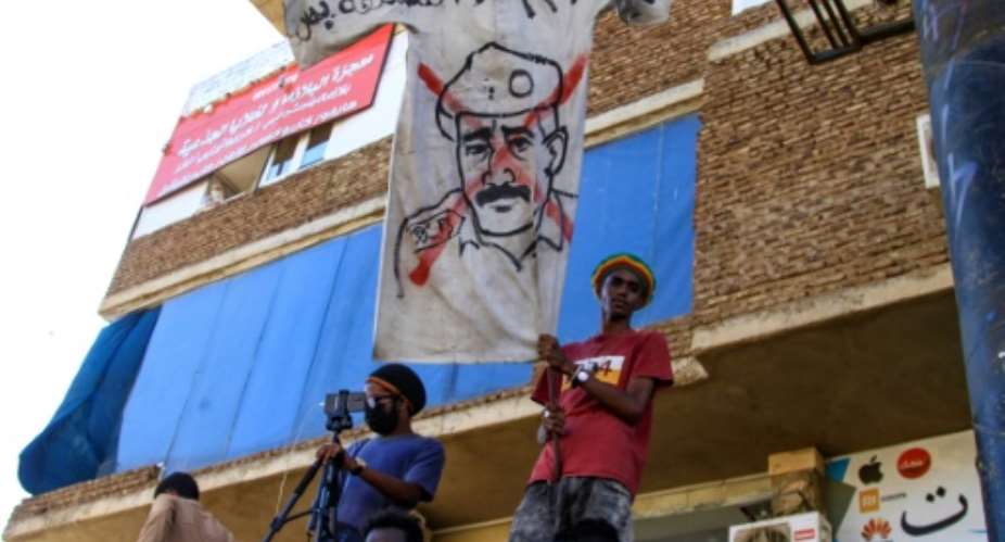 Sudanese protesters fly a banner bearing a crossed out image of coup leader Abdel Fattah al-Burhan, as they take to the streets to call for justice for those killed since last year's military power grab.  By - AFP