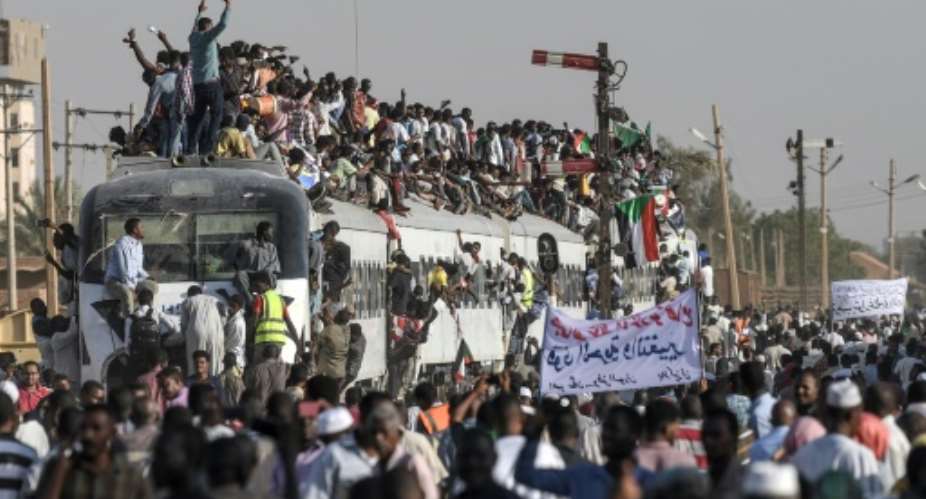 Sudanese protesters from the city of Atbara -- where demonstrations against deposed president Omar al-Bashir began more than four months ago -- cheer upon arrival at Bahari station in Khartoum on Tuesday.  By OZAN KOSE AFP