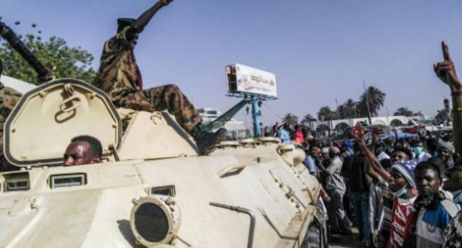 Sudanese protesters salute a military armoured vehicle at a demonstration in front of the army headquarters in Khartoum, as some ranks appear to be tiling towards the rallies.  By - AFP