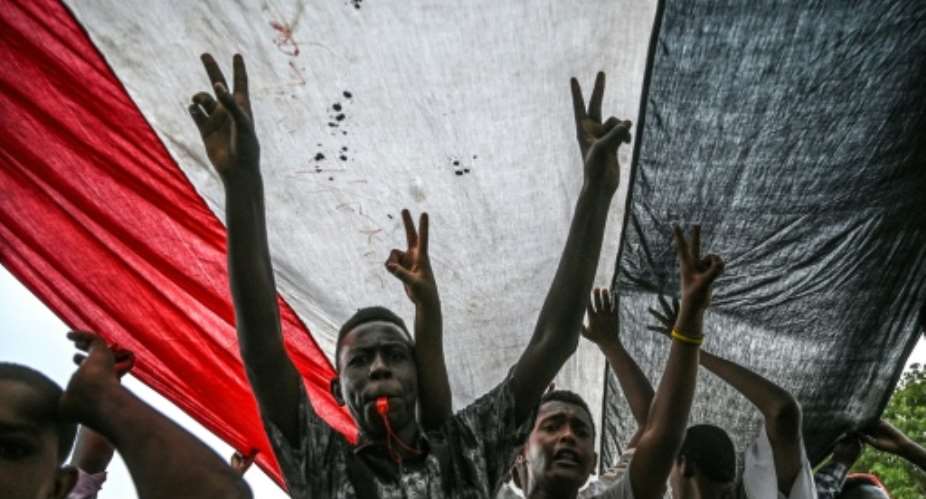 Sudanese protesters shout slogans and flash victory signs during a rally outside the army complex in Sudan's capital Khartoum.  By OZAN KOSE AFP