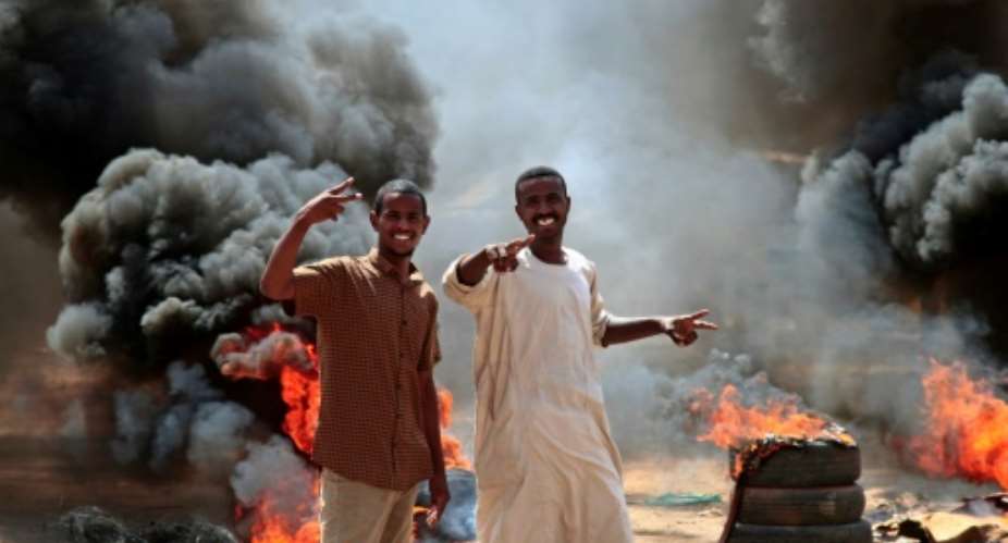 Sudanese protesters stand at a roadblock made of buring tyres in the capital Khartoum on October 26.  By - AFP