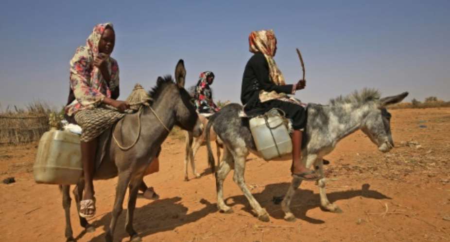 Sudanese women transport water in Darfur: the arid region remains awash with weapons and has seen a renewed spike in deadly violence in recent months triggered by disputes mainly over land, livestock and access to water and grazing.  By ASHRAF SHAZLY AFP