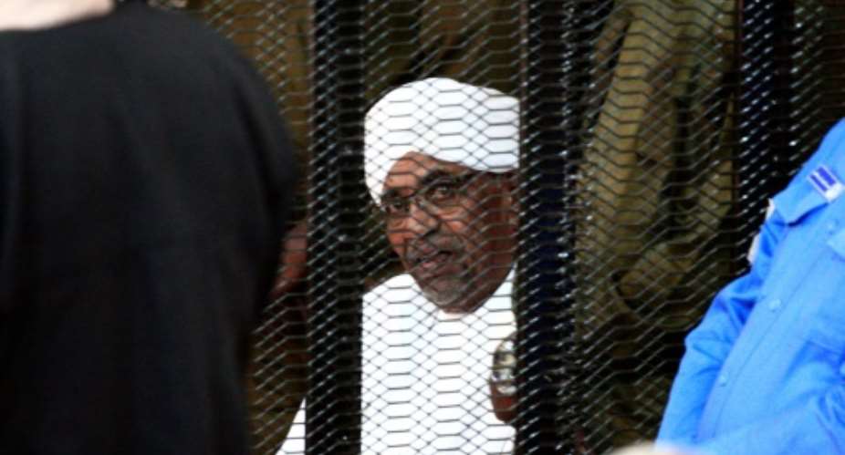 Sudan's deposed ruler Omar al-Bashir sits in a defendant's cage during his corruption trial in Khartoum.  By Ebrahim HAMID AFP