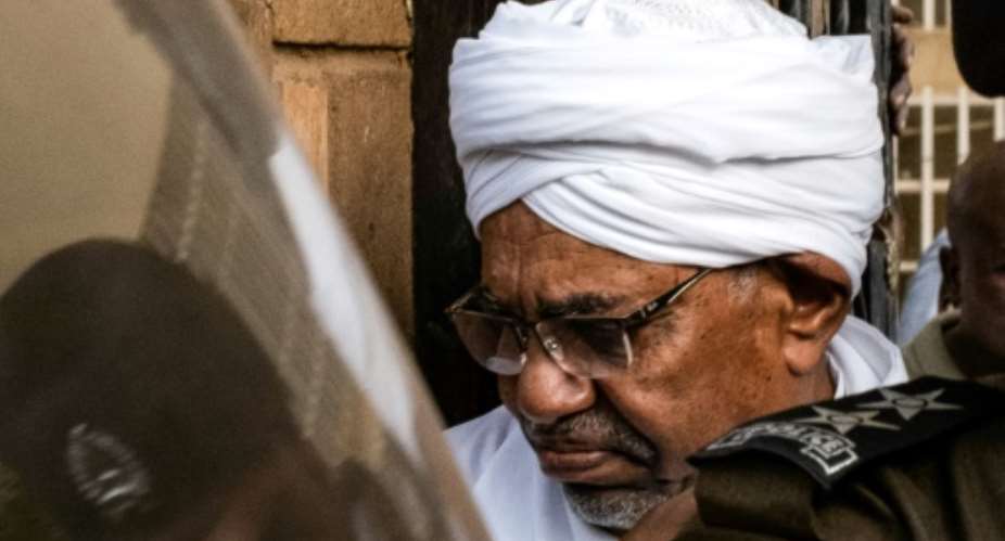 Sudan's ousted president Omar al-Bashir is escorted into a vehicle as he returns to prison after appearing before prosecutors over charges of corruption and illegal possession of foreign currency.  By Yasuyoshi CHIBA AFP