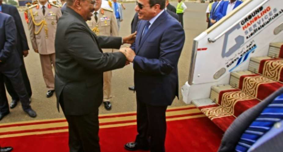 Sudan's President Omar al-Bashir C-L embraces his Egyptian counterpart Abdel-Fattah al-Sisi C-R upon the latter's arrival at Khartoum International Airport  on October 25, 2018.  By ASHRAF SHAZLY AFP
