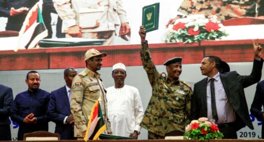 Sudan's protest leader Ahmad Rabie R, flashes the victory gesture alongside General Abdel Fattah al-Burhan 2nd-R, the chief of the military council, after signing the constitutional declaration on Saturday.  By Ebrahim HAMID AFP