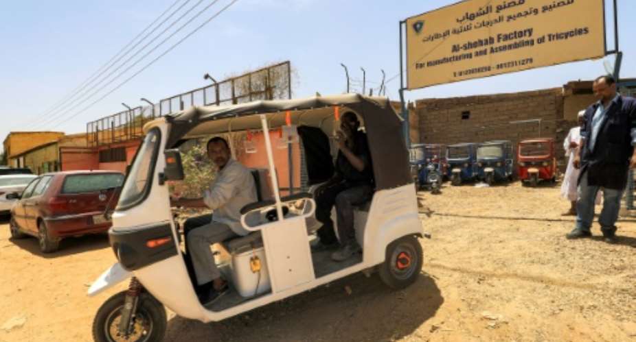 Sudanse workers test a new electric tuk-tuk.  By ASHRAF SHAZLY AFP