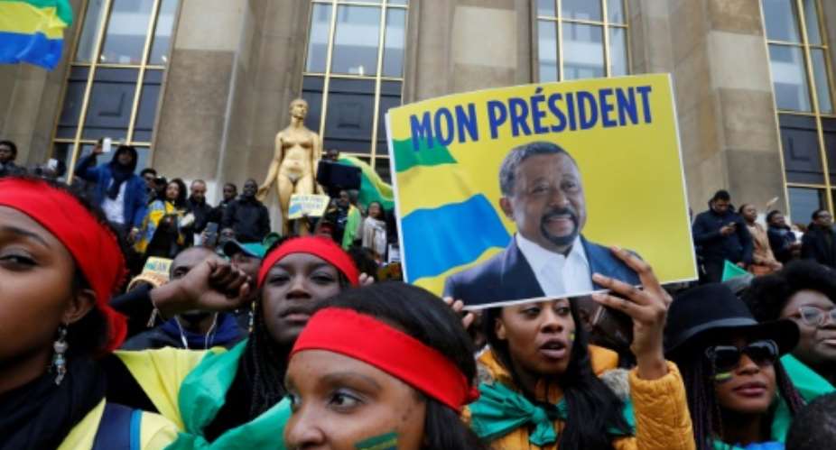 Supporters of Gabonese opposition leader Jean Ping  wrapped in Gabonese flags gesture after his speech on October 29, 2016 on the Human Rights Esplanade in Paris.  By FRANCOIS GUILLOT (AFP/File)