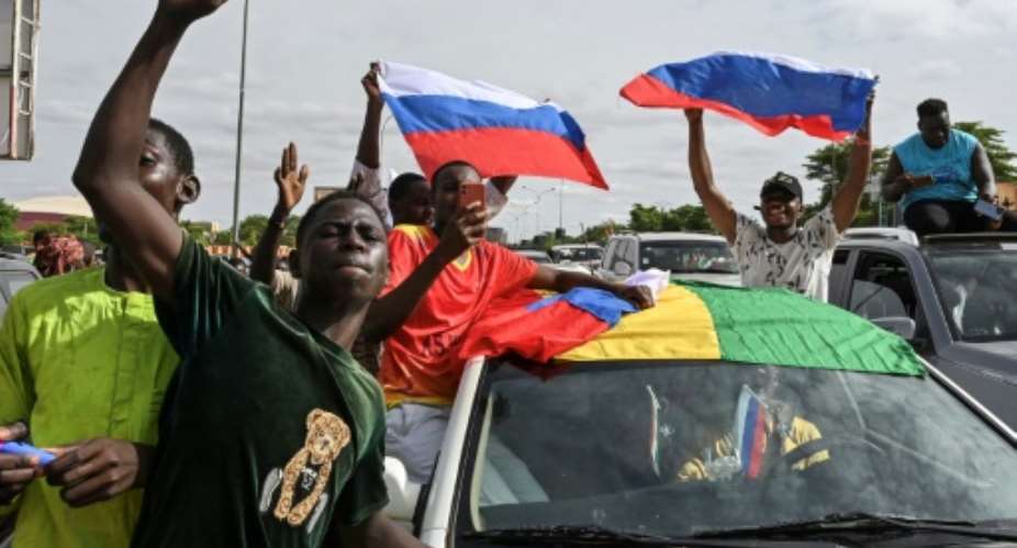 Supporters of Niger's military takeover wave Russian flags as they demonstrate in Niamey.  By - AFP