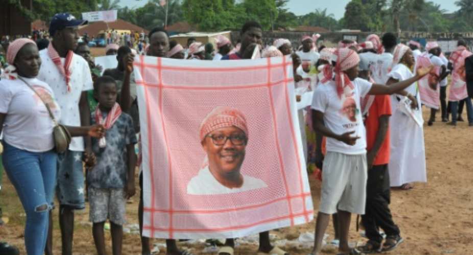 Supporters of President Umaro Sissoco Embalo show a red keffiyeh bearing his image during a political rally in Bissau on November 11, 2025.  By SAMBA BALDE (AFP)