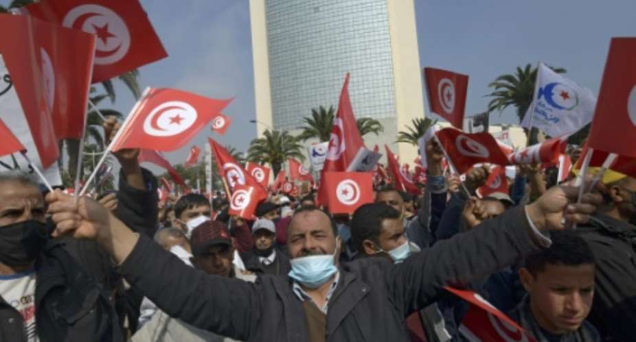 Supporters of Tunisia's Islamist-inspired Ennahdha party wave national flags during a demonstration in Tunis in support of the government following a cabinet reshuffle rejected by the country's president.  By FETHI BELAID AFP
