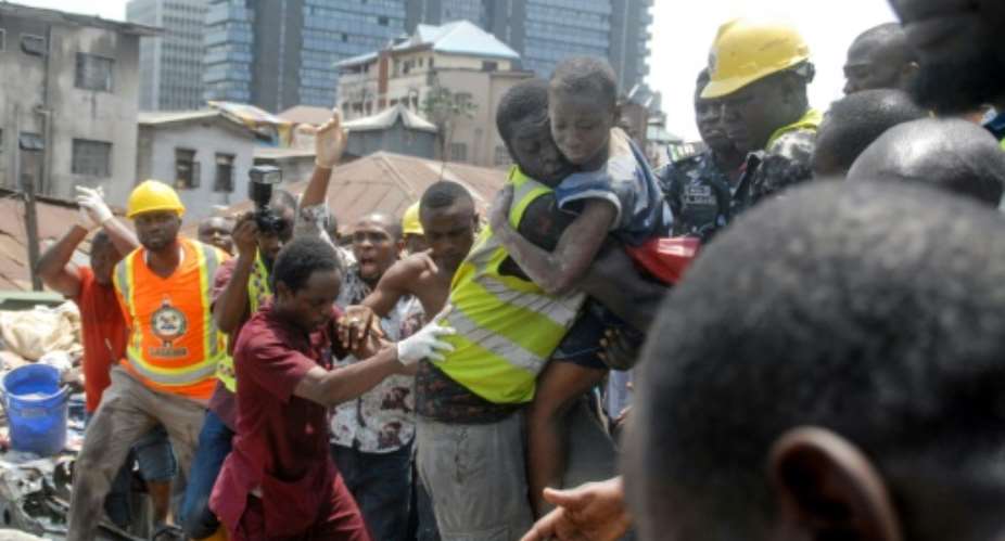Survivor: Emergency workers pluck a child from the collapsed building. The disaster left 20 dead, according to a new toll.  By SEGUN OGUNFEYITIMI AFP