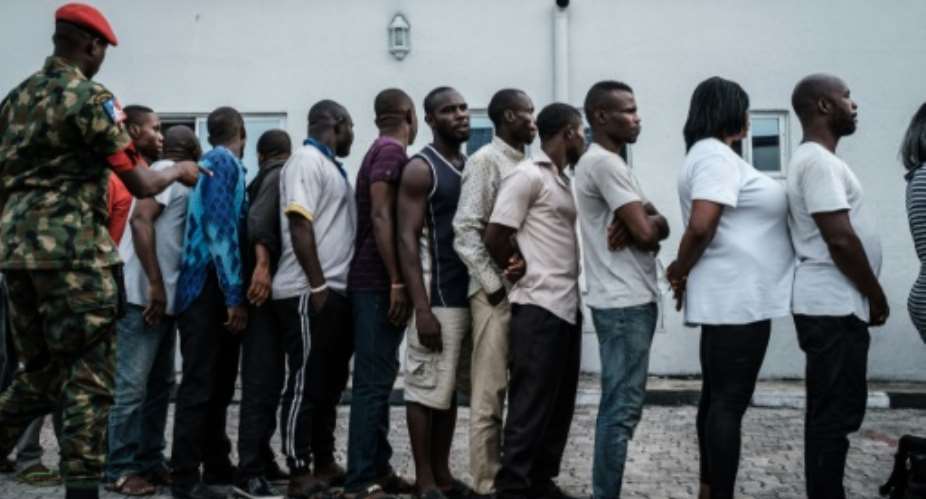 Suspects who were arrested by Nigerian Army personnel on election day in connection with various alleged electoral offenses, including stealing a carton of presidential ballot papers, stand in line to be handed over to police in Port Harcourt.  By Yasuyoshi CHIBA AFP