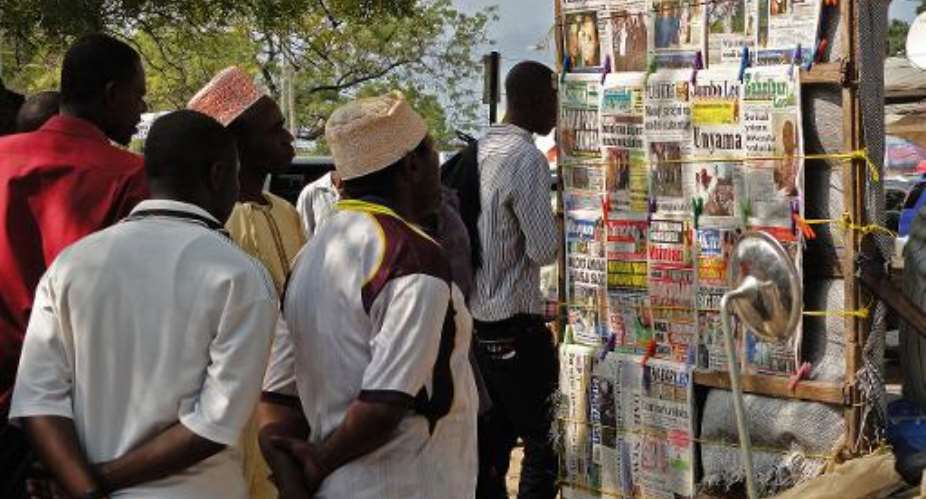 Locals look at a newspaper stand in Zanzibar, Tanzania, on August 9, 2013.  By Issa Yusuf AFPFile