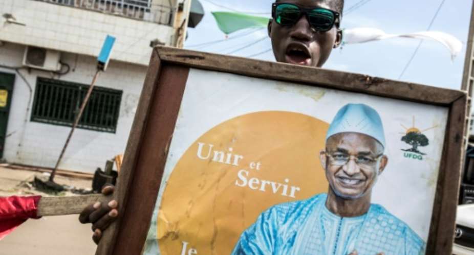 Tension: A supporter holds up a poster for Cellou Dalein Diallo in the run-up to the elections.  By JOHN WESSELS AFP