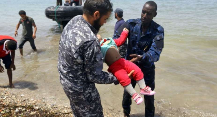 The body of a baby who died in a shipwreck off the coast of Libya is carried ashore in al-Hmidiya, east of the capital Tripoli on June 29, 2018.  By Mahmud TURKIA AFP