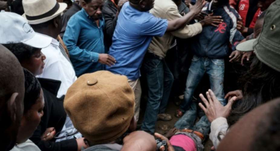 The discovery of four bodies in the Mathare slum drew a large crowd, including Kenyan opposition leader Raila Odinga, seen wearing a white hat.  By YASUYOSHI CHIBA AFP