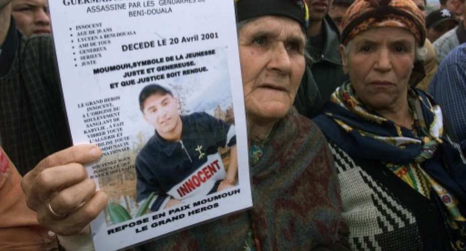 The grandmother of Massinissa Guermah, a teenager killed by Algerian  police in April 2001, holds aloft his picture in May that year, amid protests in the country's Berber heartland.  By - AFPFile