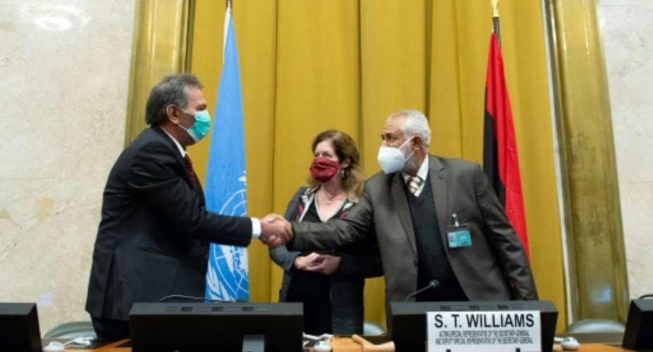 The heads of the rival Libyan delegations shake hands in front of the UN envoy after agreeing to a permanent ceasefire.  By Violaine Martin UNITED NATIONSAFP