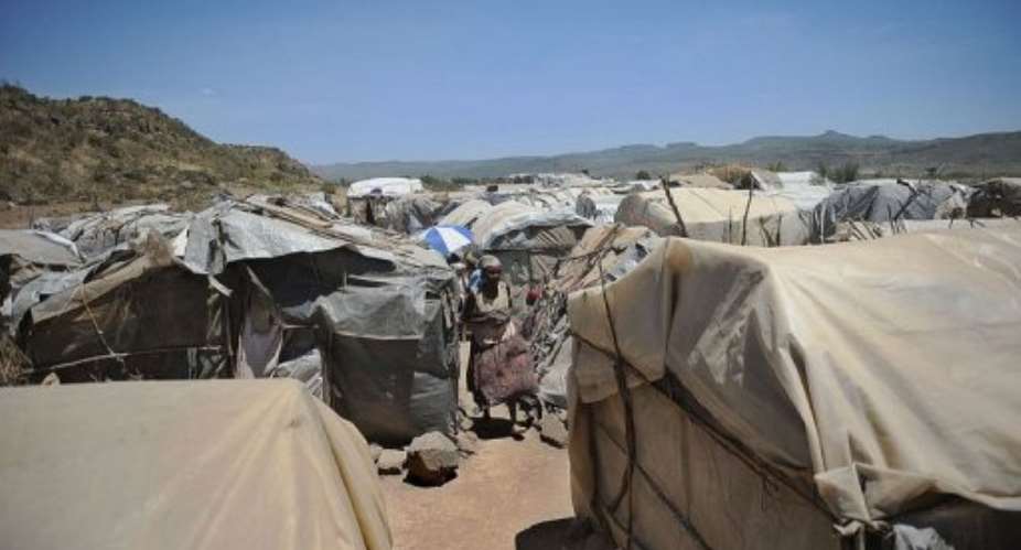 A Kenyan woman, resident of a camp for the internally displaced, walks by makeshift shelters, on February 18, 2013.  By Tony Karumba (AFP)