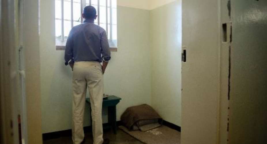 US President Barack Obama looks out the window from the cell where Nelson Mandela was once jailed on Robben Island, on June 30, 2013.  By Jim Watson AFPFile