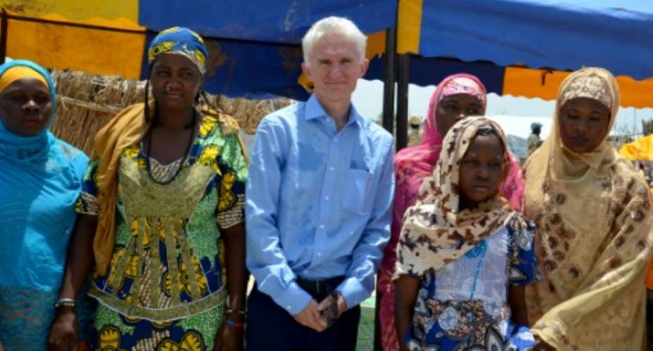 This photo taken on September 10, 2017 shows UN Under Secretary-General for Humanitarian Affairs OCHA and Emergency Relief Coordinator Mark Lowcock posing with women  at a camp for refugees and internally displaced persons  in southeast Niger.  By BOUREIMA HAMA AFPFile