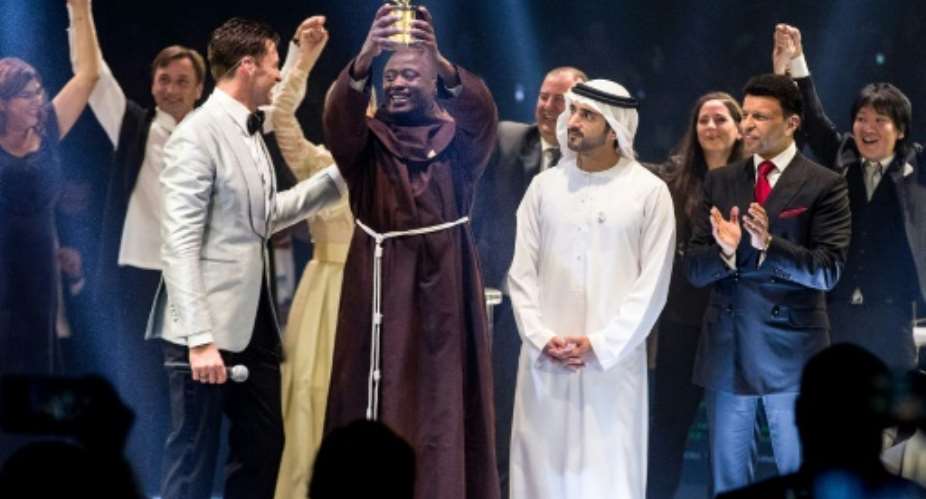 This picture provided on March 24, 2019 by the Global Education and Skills Forum of the Varkey Foundation, shows Kenyan teacher Peter Tabichi C in Dubai holding up the trophy for world's best teacher which comes with a prize of 1 million.  By - Global Education and Skills ForumAFP