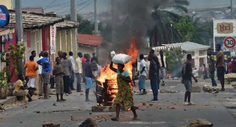 A woman walks past a burning barricade in the Kinanira neighborhood of Burundi's capital Bujumbura on May 21, 2015.  By Carl De Souza AFP