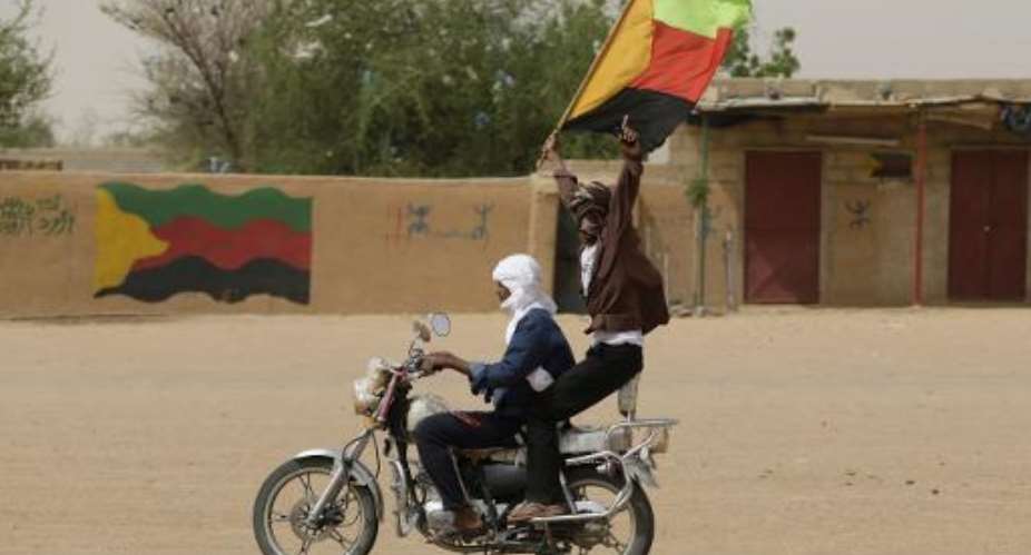 A Tuareg man waves the flag of the National Movement for the Liberation of Azawad (MLNA) during a demonstration on July 28, 2013 in Kidal.  By Kenzo Tribouillard (AFP/File)