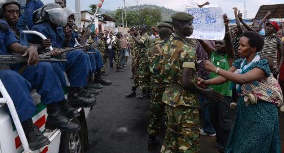 Burundian soldiers control protesters facing riot police seated in a pickup truck in Musaga, on the outskirts of Bujumbura, on April 29, 2015, during demonstrations against the president's bid for a third term.  By Simon Maina AFP