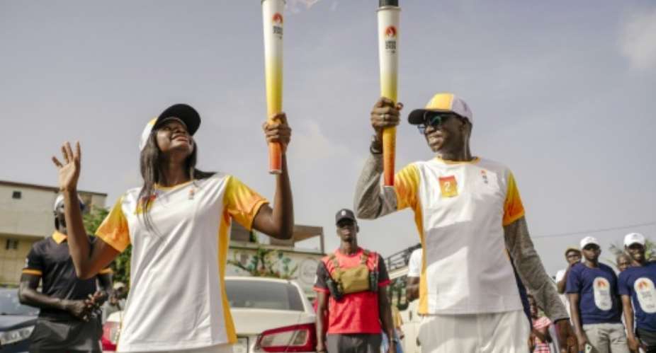 Torchbearers carry the Youth Olympic Flame during its tour through Dakar in September 2026.  By Carmen Abd Ali (AFP/File)
