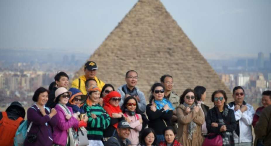 Tourists pose for a group picture at the Giza pyramids  on the southwestern outskirts of the Egyptian capital Cairo on December 29, 2018.  By MOHAMED EL-SHAHED AFP
