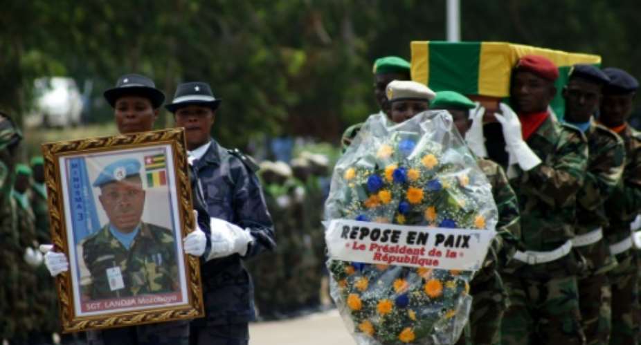 Police officers and members of the Togolese army carry the casket and a picture of Sgt Landja Mozoboyo, one of the five Togolese peacekeepers killed in Mali, during a commemoration ceremony in Lome on July 8, 2016.  By Emile Kouton AFP