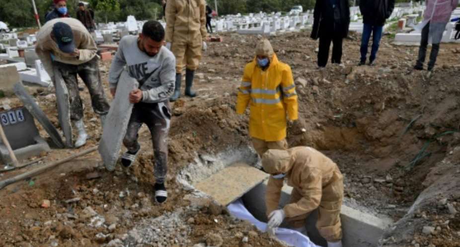 Tunis municipality employees bury the body of a Covid-19 victim at the Jellaz cemetery in the capital Tunis.  By FETHI BELAID AFP