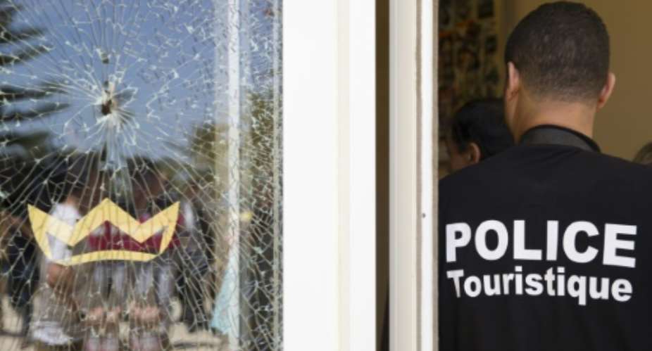 A member of the Tunisian security forces stands guard near a bullet hole on a window at the Riu Imperial Marhaba Hotel in Port el Kantaoui on June 29, 2015.  By Kenzo Tribouillard AFP
