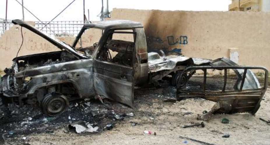 A burnt out vehicle is seen on the side of the road leading to the airport in Tripoli, Libya, on May 19, 2014, following attacks by armed groups.  By Mahmud Turkia (AFP/File)