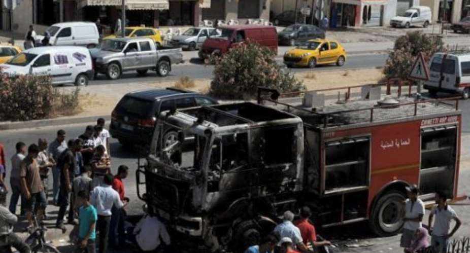 People look a charred truck in Essijoumi.  By Fethi Belaid AFP