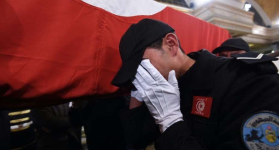 A Tunisian policeman mourns November 25, 2015, as he carries the coffin of a member of the presidential guard killed in a bomb blast on a bus in central Tunis the previous day.  By Fethi Belaid AFP