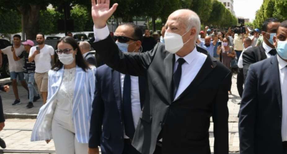 Tunisian President Kais Saied, who has suspended parliament, waves as he walks with security guards in central Tunis on August 1, 2021.  By - TUNISIAN PRESIDENCYAFPFile