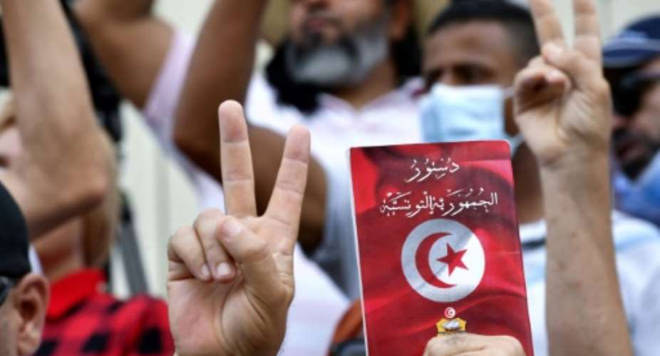 Tunisian protesters wave copies of the constitution as they march through the capital to demand an end to the sweeping extraordinary powers assumed by President Kais Saied in July.  By FETHI BELAID AFP