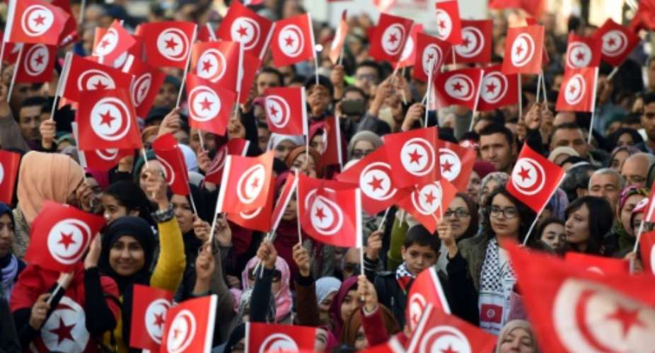 Tunisians wave national flags and shout slogans on January 14, 2016, during a rally to mark the fifth anniversary of the 2011 revolution.  By Fethi Belaid AFPFile